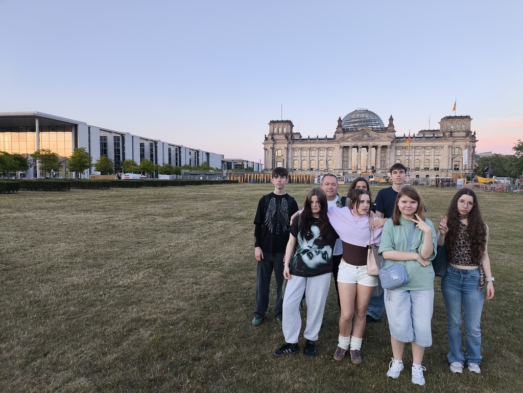 Uczniowie TME z opiekunem na trawniku przed Reichstagiem o zachodzie słońca